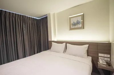 a hotel room with a white bed and a window at Sovereign Group Hotel at Pratunam in Bangkok