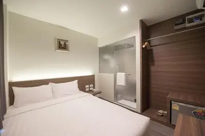 a bedroom with a large white bed and a bathroom at Sovereign Group Hotel at Pratunam in Bangkok