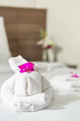 a stack of towels with a pink flower on top at Sovereign Group Hotel at Pratunam in Bangkok