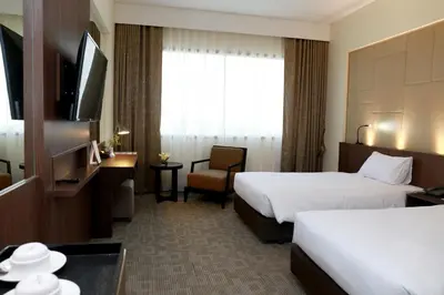 a hotel room with two beds and a television at Louis Tavern Hotel in Bangkok