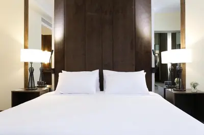 a bedroom with a large white bed with two lamps at Louis Tavern Hotel in Bangkok