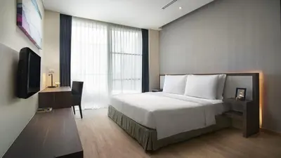 a bedroom with a bed and a desk and a television at Shama Sukhumvit Bangkok in Bangkok