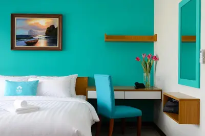 a bedroom with a bed and a desk with a blue wall at SiRi Ratchada Bangkok in Bangkok