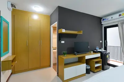 a bedroom with a bed and a desk with a television at SiRi Ratchada Bangkok in Bangkok