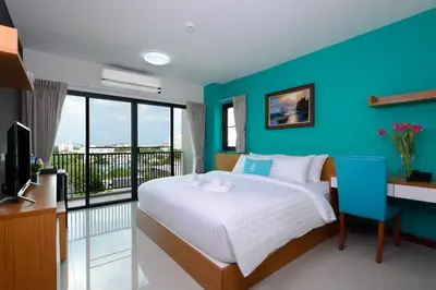 a bedroom with a blue wall and a bed and a desk at SiRi Ratchada Bangkok in Bangkok