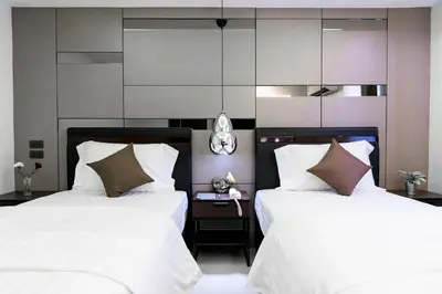two beds in a bedroom with white sheets and brown pillows at The Connex Asoke in Bangkok