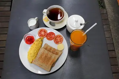 a plate of breakfast food with eggs tomatoes and a cup of coffee at Lamphuhouse Bangkok in Bangkok