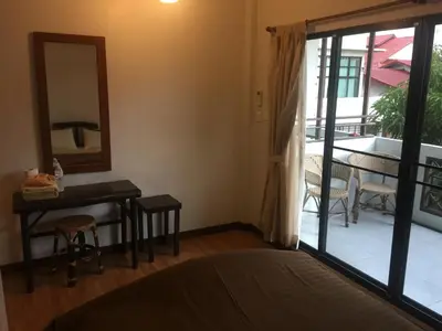 a bedroom with a bed and a table and a mirror at Lamphuhouse Bangkok in Bangkok