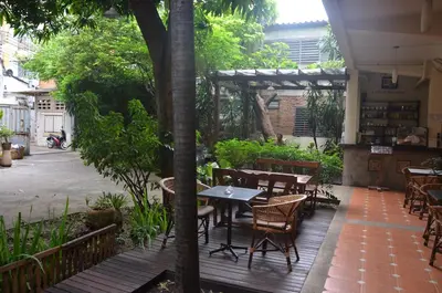 an outdoor patio with tables and chairs and trees at Lamphuhouse Bangkok in Bangkok