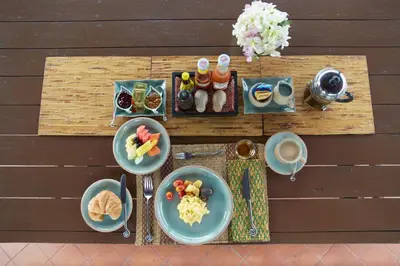 a table with plates of food and cups of coffee at Chakrabongse Villas in Bangkok
