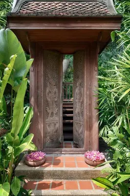 a wooden entrance to a building with some plants at Chakrabongse Villas in Bangkok