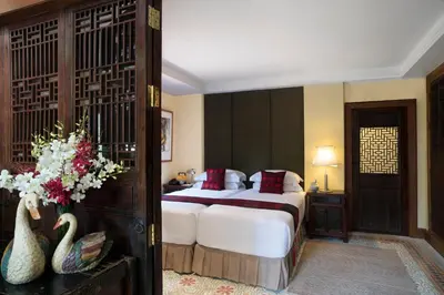 a bedroom with a large bed with white sheets and red pillows at Chakrabongse Villas in Bangkok