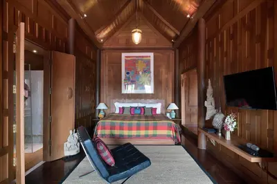a bedroom with a bed and a tv and a chair at Chakrabongse Villas in Bangkok