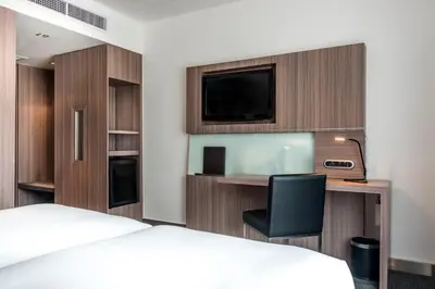 a hotel room with a bed and a desk and a tv at Hilton Garden Inn Bangkok Silom in Bangkok