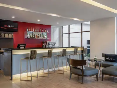 a bar in a restaurant with a red wall at Ibis Bangkok Riverside in Bangkok