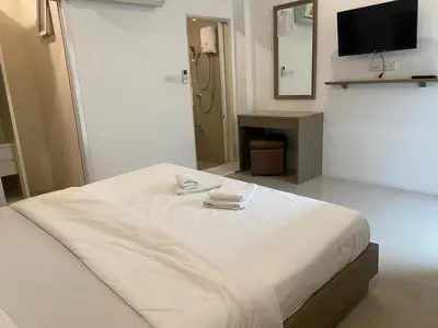 a white bed in a room with a television at S.E.T Thanmongkol Residence in Bangkok