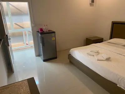 a bedroom with a bed and a small refrigerator at S.E.T Thanmongkol Residence in Bangkok