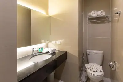a bathroom with a sink and a toilet and a mirror at Mida Hotel Don Mueang Airport in Bangkok