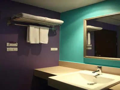 a bathroom with a sink and a mirror and towels at Sawasdee Hotel @ Sukhumvit Soi 8 in Bangkok