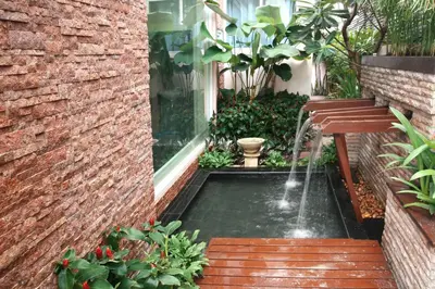 a garden with a water fountain in a courtyard at Mirth Sathorn Hotel in Bangkok