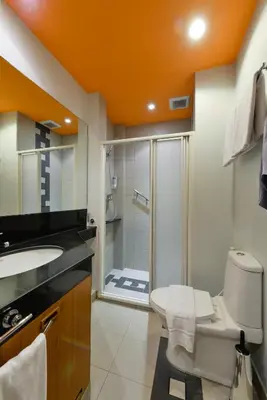 an orange bathroom with a toilet and a shower at iCheck inn Sukhumvit 19 in Bangkok