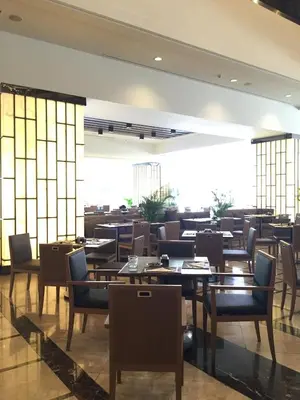 a restaurant with wooden tables and chairs and a large window at Arnoma Hotel Bangkok in Bangkok
