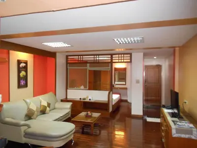 a living room with a couch and a tv at B.S. Court Hotel Sathorn in Bangkok