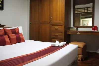 a bedroom with a bed with a dresser and a drawer at B.S. Court Hotel Sathorn in Bangkok