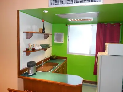 a green kitchen with a sink and a refrigerator at B.S. Court Hotel Sathorn in Bangkok