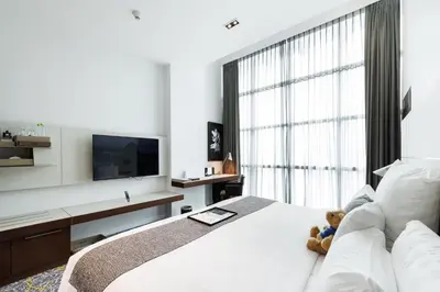 a bedroom with a white bed with a teddy bear on it at S31 Sukhumvit Hotel in Bangkok
