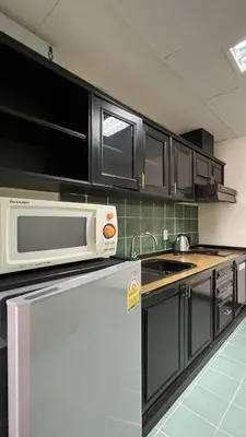 a kitchen with black cabinets and a microwave at Yellow Ribbon Hills Boutique Suites in Bangkok