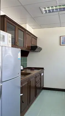 a kitchen with a white refrigerator and wooden cabinets at Yellow Ribbon Hills Boutique Suites in Bangkok