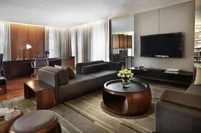 a living room with a couch and a tv at Hansar Bangkok Hotel in Bangkok
