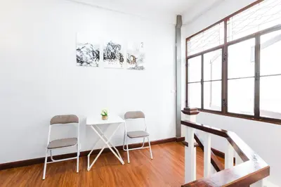 a white room with three chairs and a table at House of Happiness in Bangkok