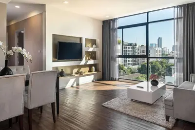 a living room with a television and a table with chairs at Metropolis Suites Bangkok, Tapestry Collection by Hilton in Bangkok