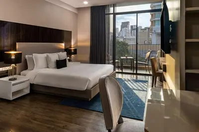 a hotel room with a bed and a balcony at Metropolis Suites Bangkok, Tapestry Collection by Hilton in Bangkok