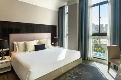 a bedroom with a large white bed and a window at Metropolis Suites Bangkok, Tapestry Collection by Hilton in Bangkok