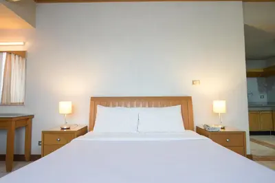 a bedroom with a large white bed and two lamps at Baan Pratoom in Bangkok