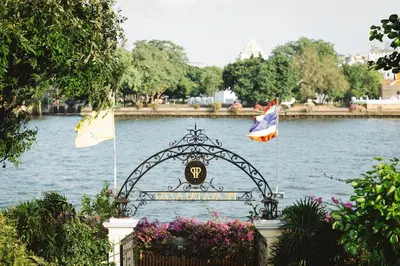 a gate with two flags in front of a body of water at Praya Palazzo in Bangkok