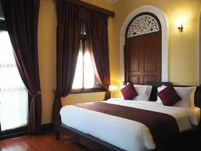 a bedroom with a large bed with red pillows at Praya Palazzo in Bangkok