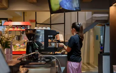 a woman preparing a drink in a coffee shop at Lub d Bangkok Siam - New Look, Across from MBK & Skytrain Access in Bangkok