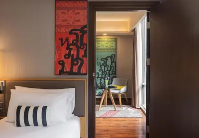 a bedroom with a bed and a room with a chair at Travelodge Sukhumvit 11 in Bangkok
