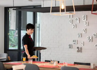a man holding a plate of food on a table at Travelodge Sukhumvit 11 in Bangkok