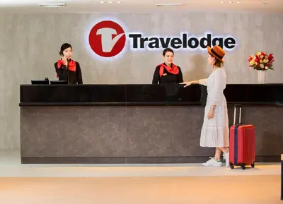 a woman is standing at a ticket counter at an airport at Travelodge Sukhumvit 11 in Bangkok