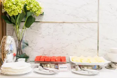 a table topped with desserts and a vase of flowers at Hotel De Bangkok in Bangkok