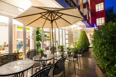 a patio with tables and chairs and an umbrella at Hotel De Bangkok in Bangkok