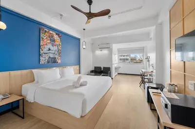 a bedroom with a large white bed and a blue wall at River View Residence in Bangkok