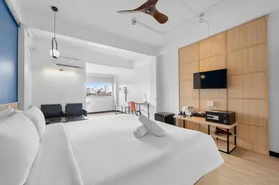 a bedroom with a white bed and a flat screen tv at River View Residence in Bangkok