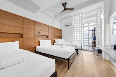 a bedroom with three beds and a window at River View Residence in Bangkok