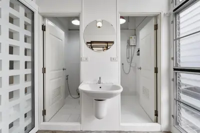 a white bathroom with a sink and a mirror at River View Residence in Bangkok